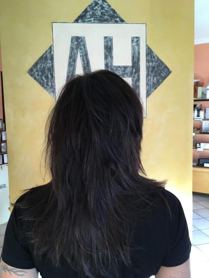 Un taglio scalato appena finito davanti al logo AH del salone